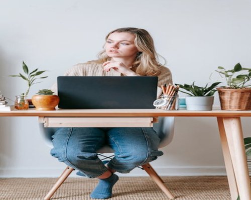 Woman looking away from her laptop screen in a home office
